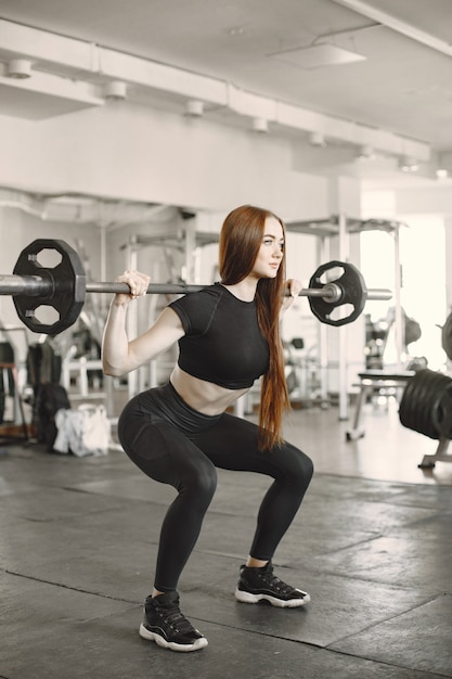 Woman doing exercise with barbell. Wearing black active wear.