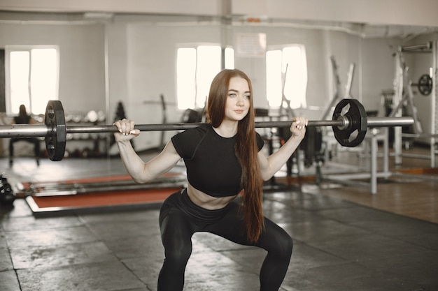 Woman doing exercise with barbell. Wearing black active wear.
