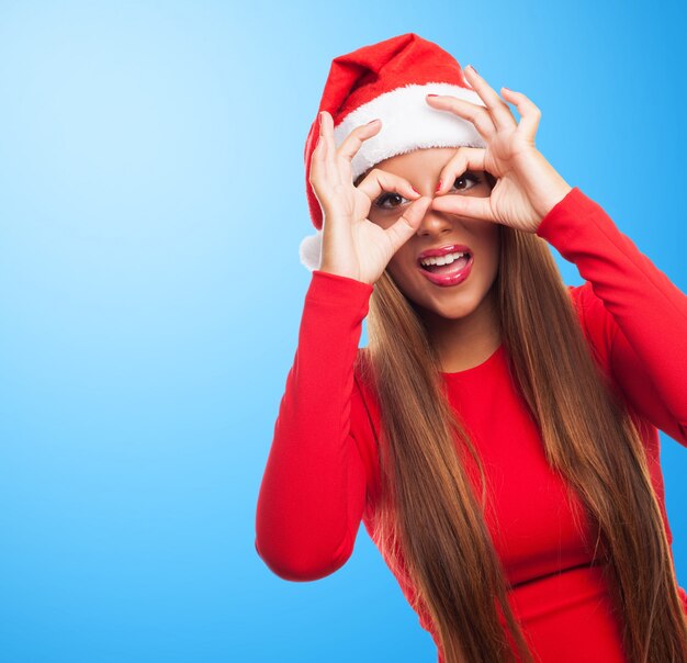 Woman doing finger glasses in a blue background
