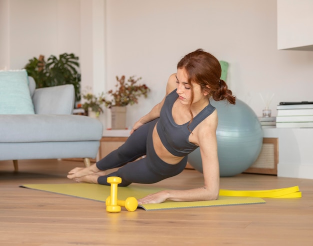 Free photo woman doing fitness at home on mat