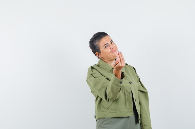 Woman doing Italian gesture in jacket, t-shirt and looking cheery.