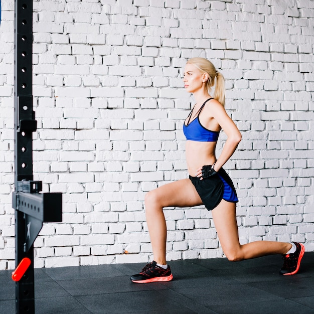 Free photo woman doing lunges near white wall