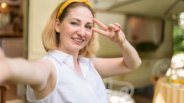 Woman doing the peace sign next to an unfocused caravan with copy space