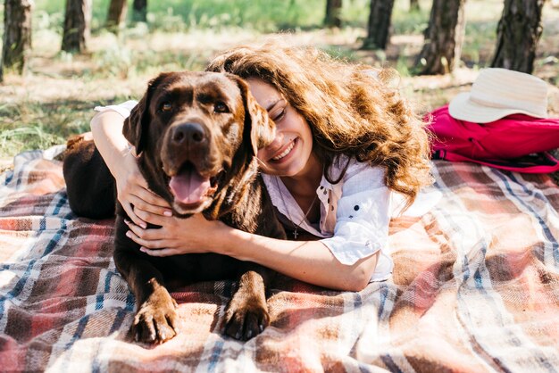 彼女の犬と一緒にピクニックをしている女性