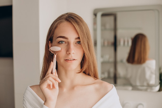 Woman doing self massage with rose quartz face roller