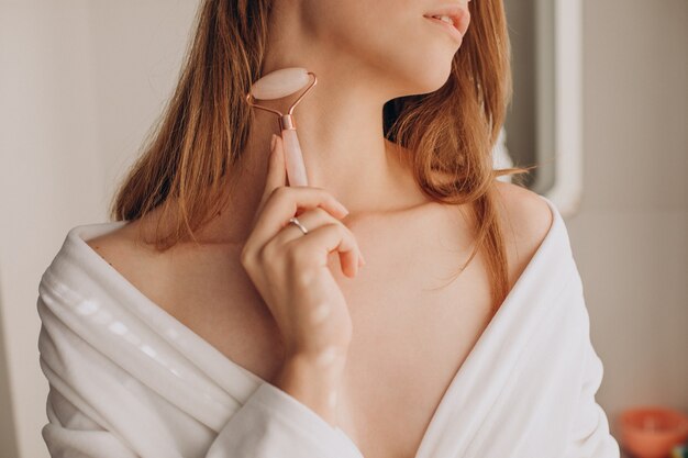 Woman doing self massage with rose quartz face roller