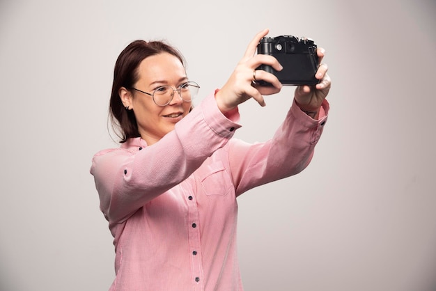 Woman doing a selfie with a camera on a white. High quality photo