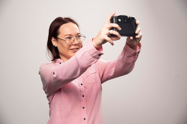 Woman doing a selfie with a camera on a white. High quality photo