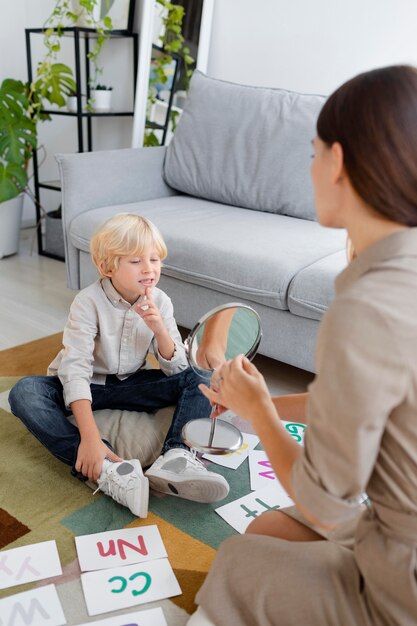 小さな金髪の少年と言語療法をしている女性