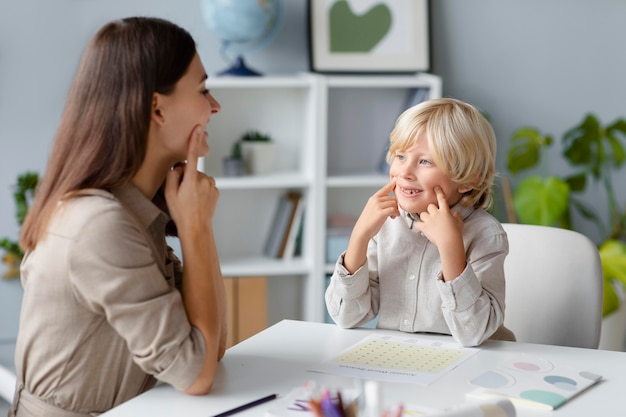 Woman doing speech therapy with a little blonde boy