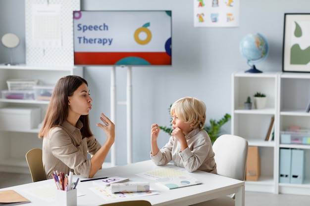 Woman doing speech therapy with a little blonde boy