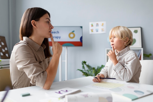 Woman doing speech therapy with a little blonde boy