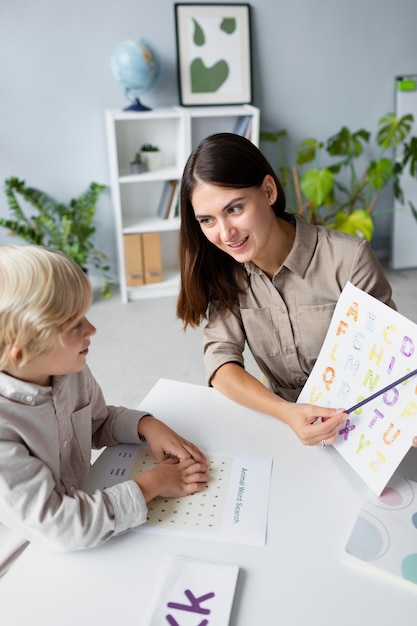 Woman doing speech therapy with a little blonde boy