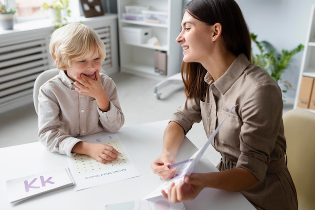 Woman doing speech therapy with a little blonde boy