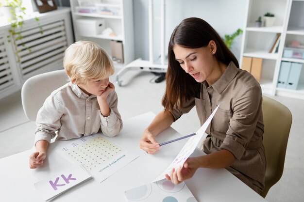 Woman doing speech therapy with a little blonde boy