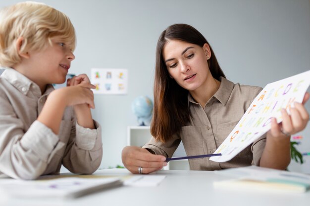 Woman doing speech therapy with a little blonde boy