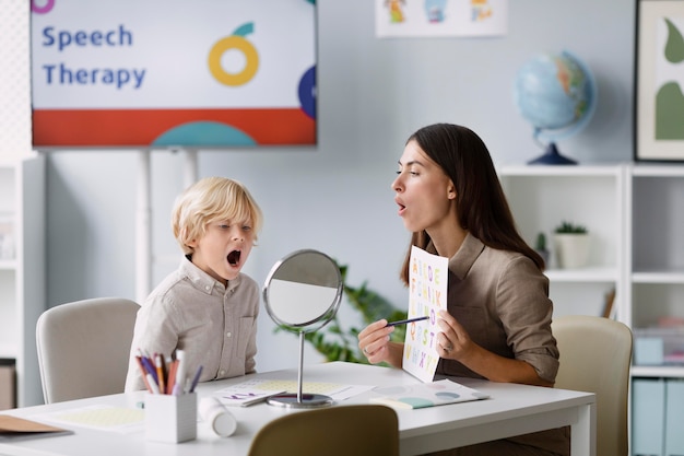 Woman doing speech therapy with a little boy at her clinic