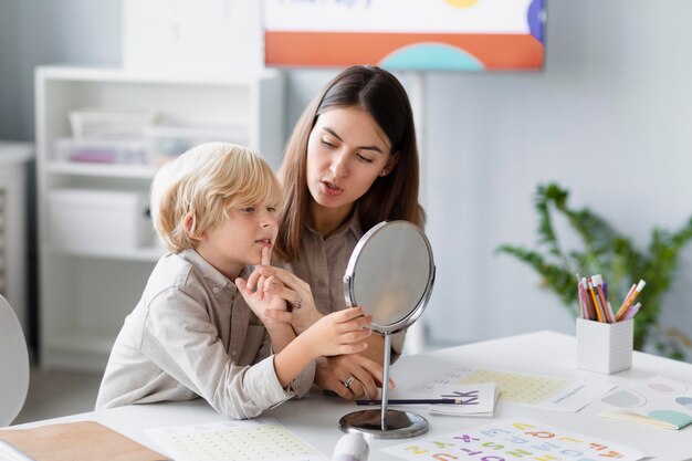 Woman doing speech therapy with a little boy at her clinic