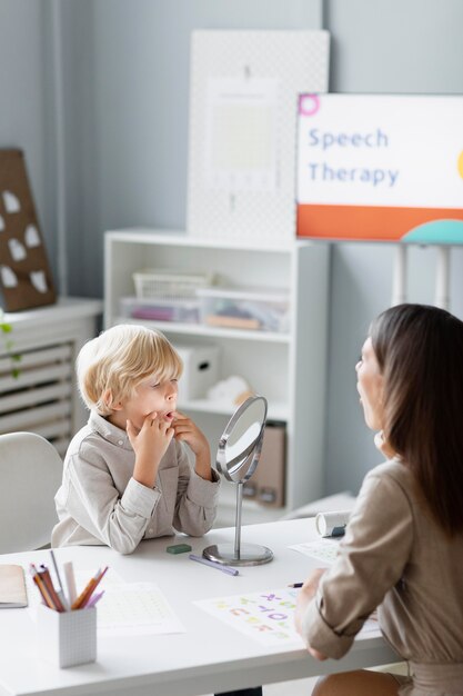 彼女のクリニックで小さな男の子と言語療法をしている女性