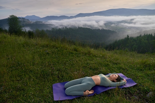 Woman doing supta varjasana pose on yoga mat