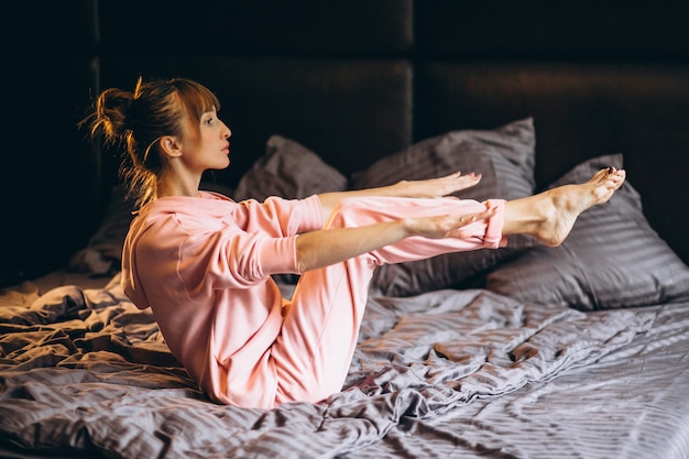 Женщина делает йогу в постели