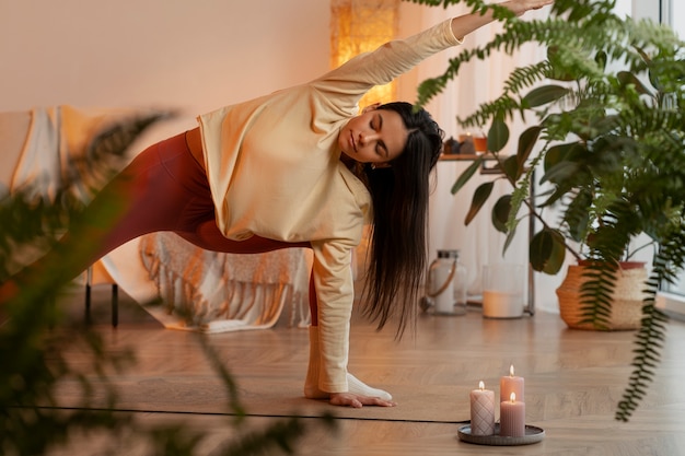 Free photo woman doing yoga indoors full shot