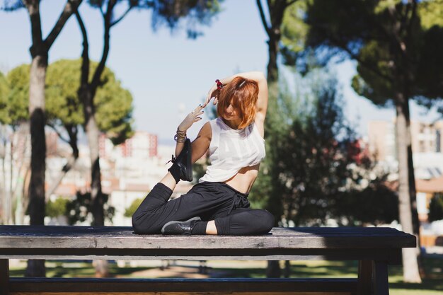 Woman doing yoga on park bench