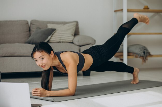 Woman doing yoga plank at home on mat