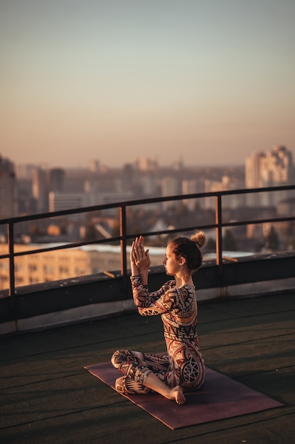 Free photo woman doing yoga on the roof of a skyscraper in big city