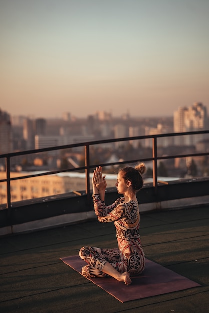 大都会の高層ビルの屋上でヨガをしている女性