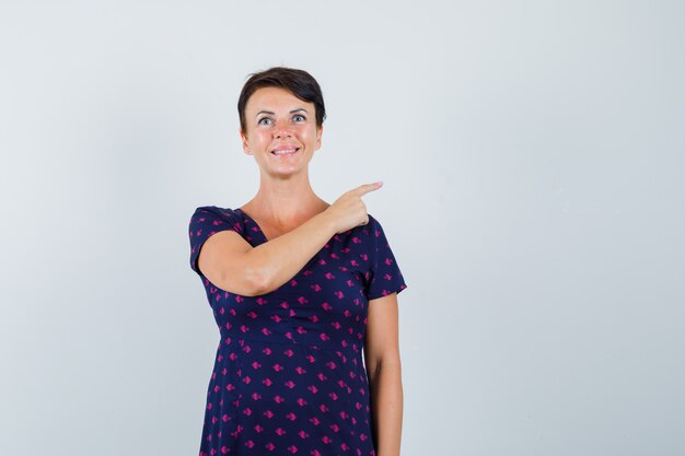 Woman in dress pointing at upper right corner and looking hopeful