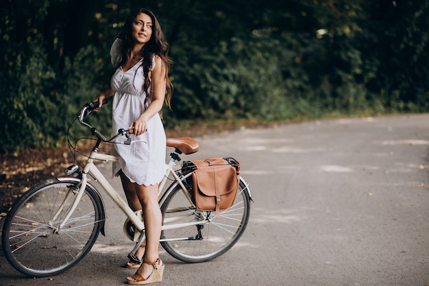 Donna in vestito che guida la bicicletta nel parco