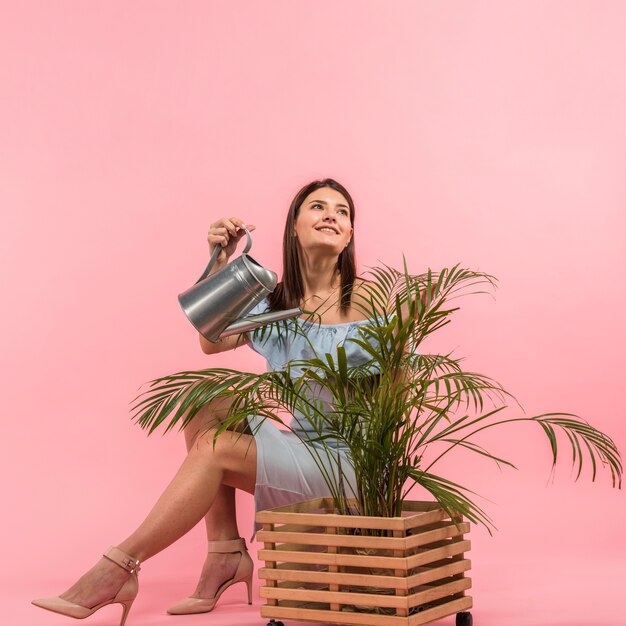 Woman in dress watering plant in pot