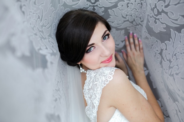 Free photo woman dressed as a bride leaning against a wall