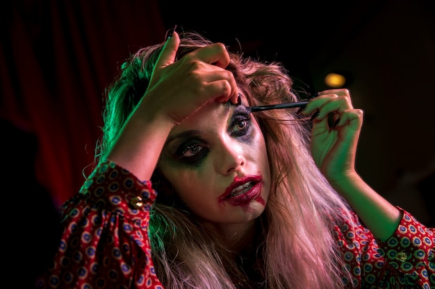 Woman dressed as a clown using make-up