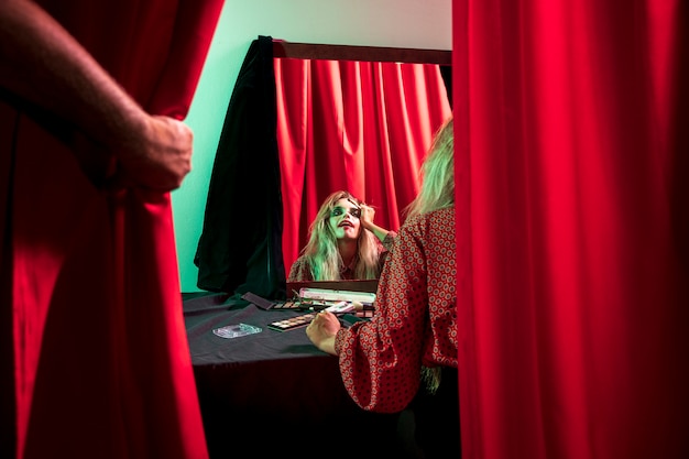 Woman dressed as a halloween clown looking in the mirror