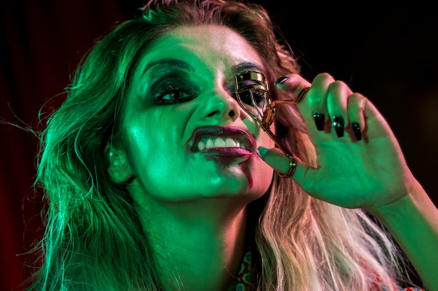 Woman dressed as joker using a eyelash curler