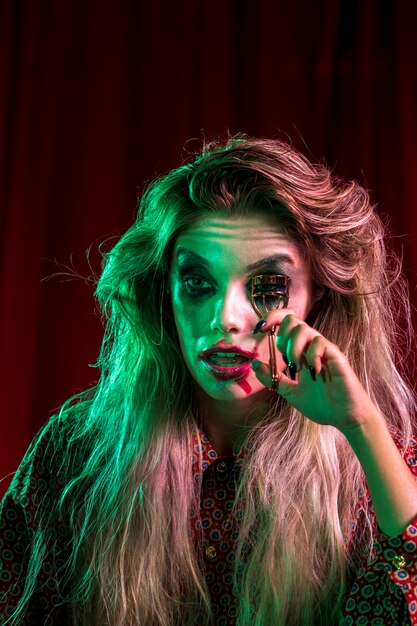 Woman dressed as joker using a eyelash curler