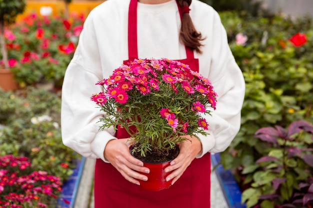 Woman dressed in gardening clothes holding flower pot