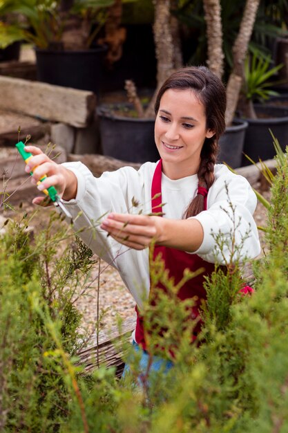 Woman dressed in gardening clothes trimming plants