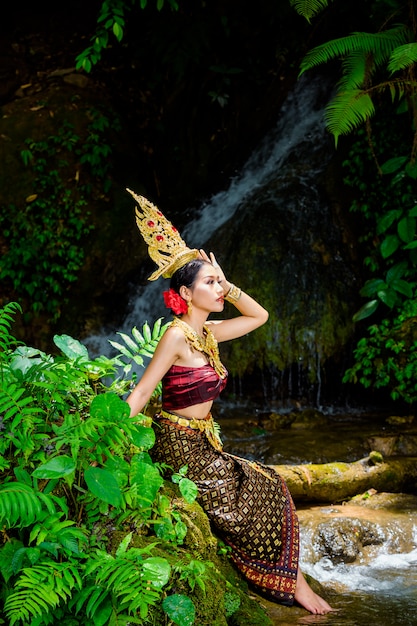 A woman dressed with an ancient Thai dress at the waterfall.