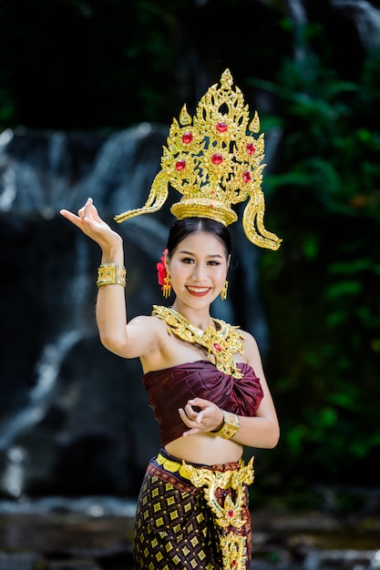 Foto gratuita una donna vestita con un abito thailandese antico presso la cascata.