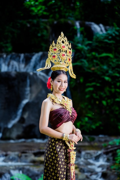 Foto gratuita una donna vestita con un abito thailandese antico presso la cascata.