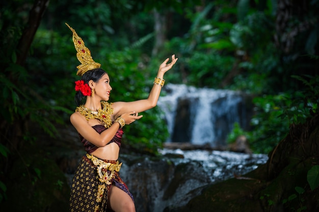 A woman dressed with an ancient Thai dress at the waterfall.