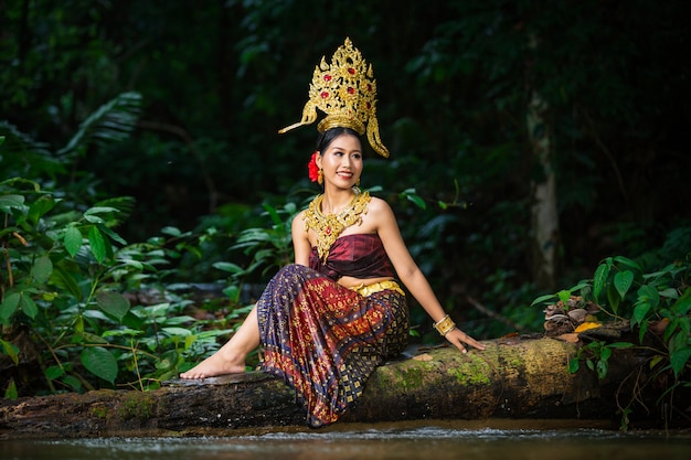 Free photo a woman dressed with an ancient thai dress at the waterfall.