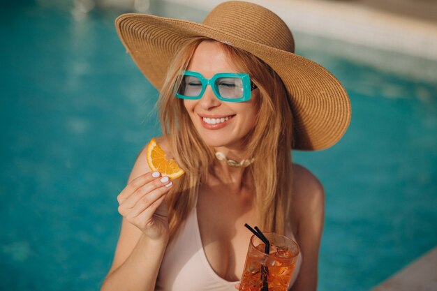 Woman drinking alcohol cocktail by the pool