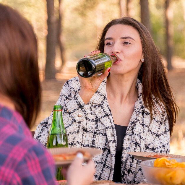 Woman drinking beer while outdoors with friends