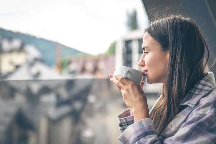 無料Photo 朝のバルコニーでコーヒーを飲む女性