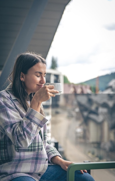 朝のバルコニーでコーヒーを飲む女性