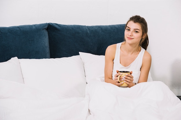 女性がベッドの中でコーヒーを飲む